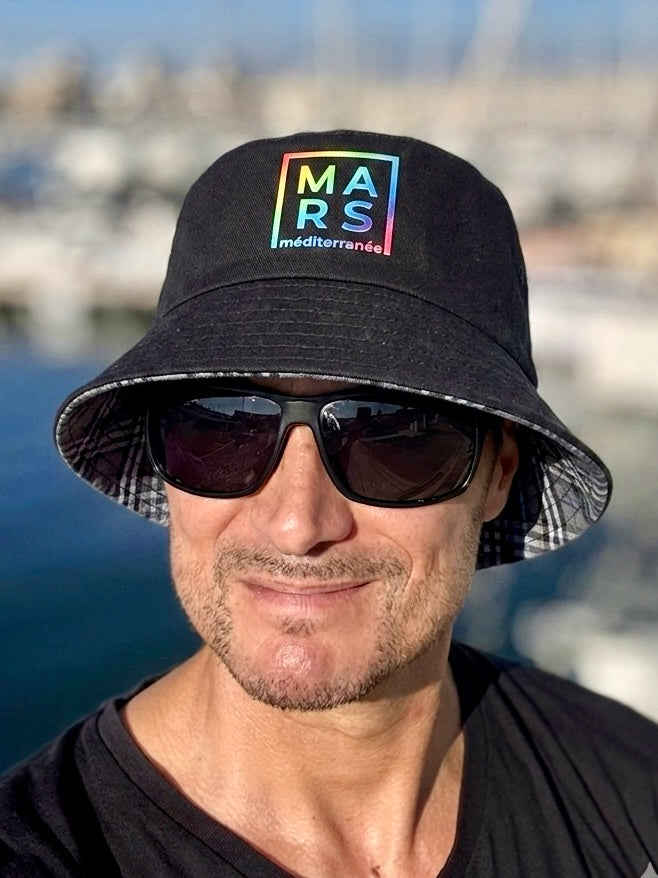 Jeune homme avec un bob noir et reversible, très tendance, avec un logo MARS en multicolore 