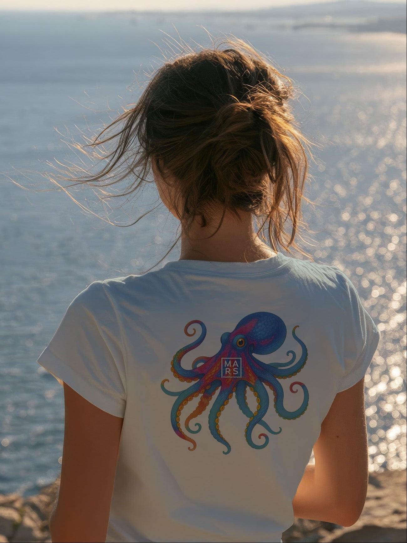 Femme au bord de mer portant un tee-shirt bleu avec une illustration de poulpe