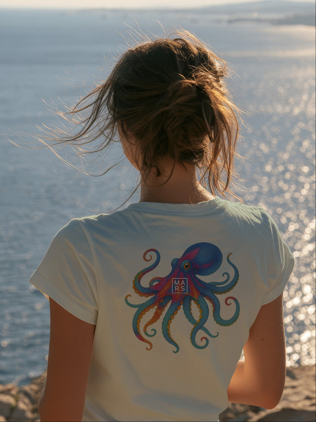 Femme au bord de mer portant un tee-shirt vert avec une illustration de poulpe