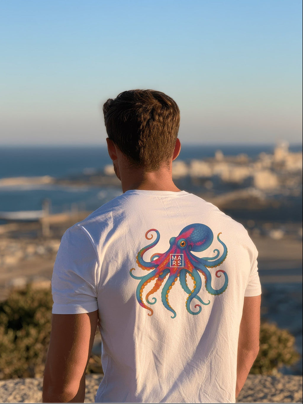 Homme au bord de mer portant un tee-shirt blanc et une illustration d‘un joli poulpe