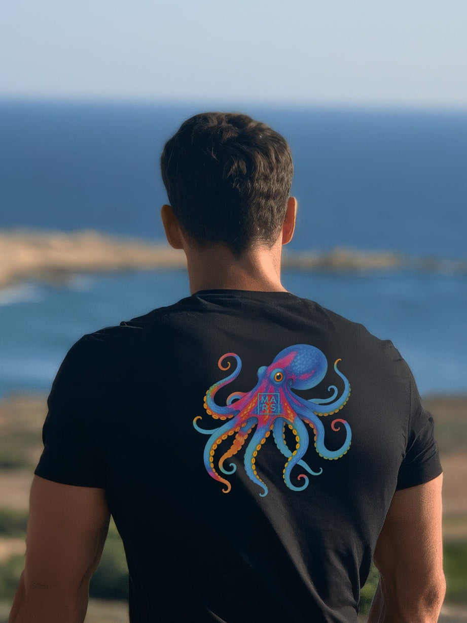 Homme au bord de mer portant un tee-shirt noir et une illustration d‘un poulpe