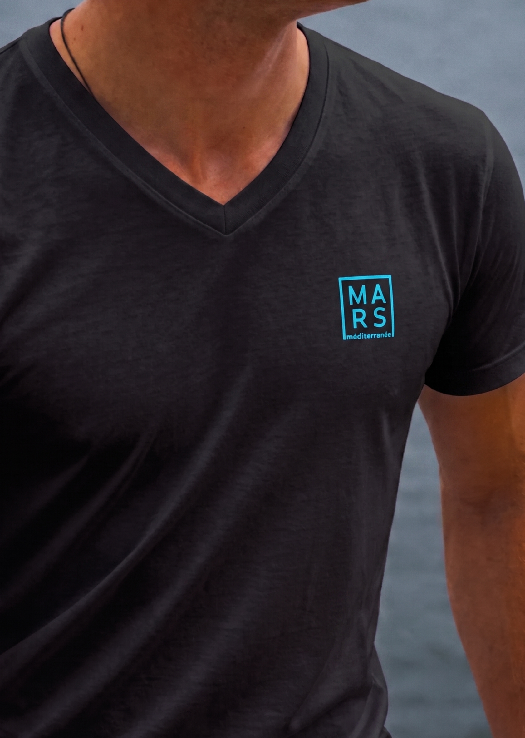 Homme portant un t-shirt noir avec un logo MARS méditerranée