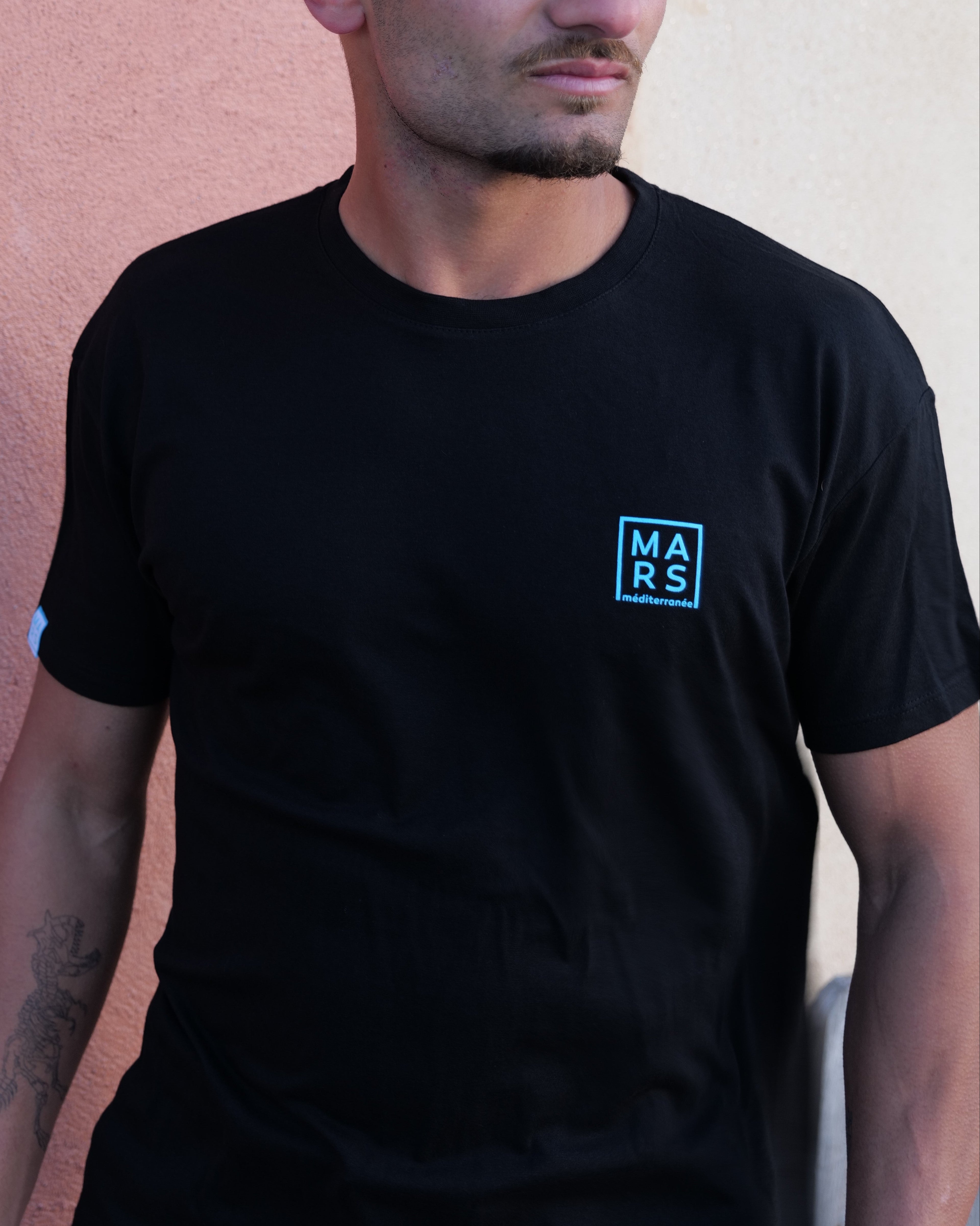 homme portant un t-shirt noir avec logo MARS méditeranée